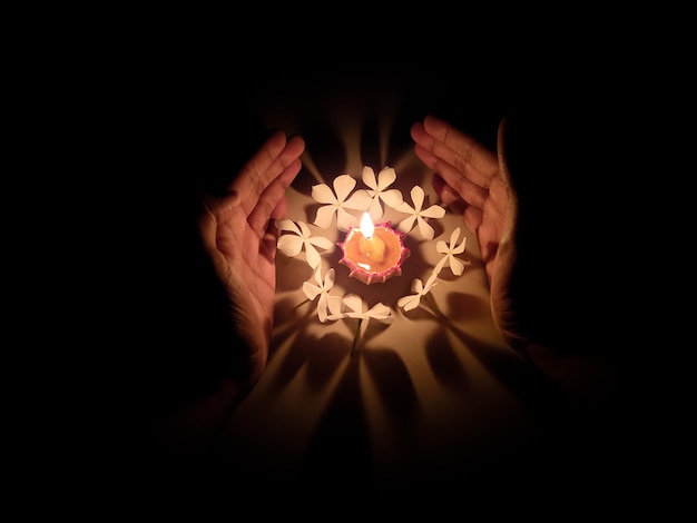 Foto close-up di una mano che tiene una candela accesa al buio