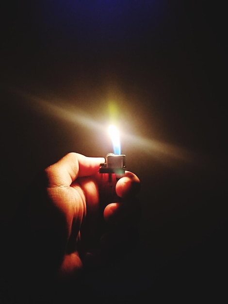 Photo close-up of hand holding lit candle