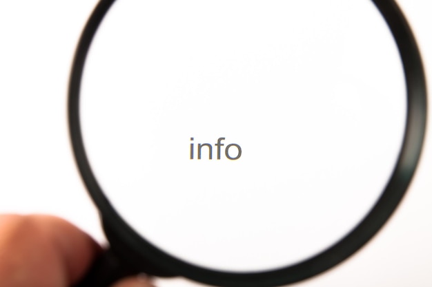 Photo close-up of hand holding magnifying glass over text against white background