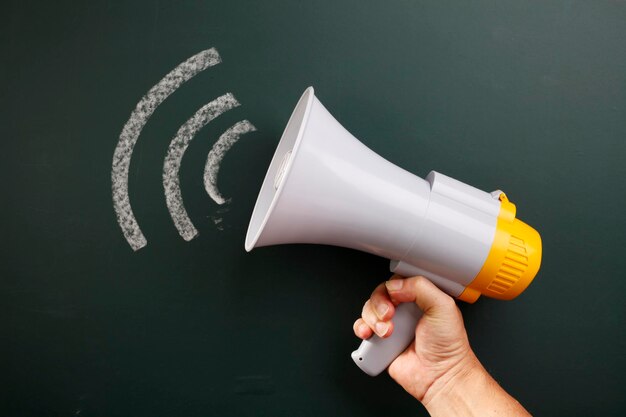 Photo close-up of hand holding megaphone over white background