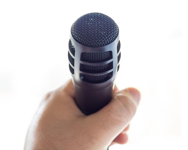 Photo close-up of hand holding microphone over white background