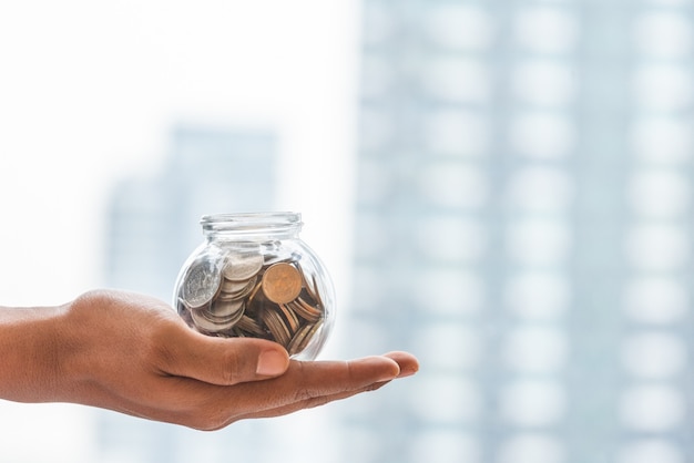 Photo close up hand holding money in the glass with copy space