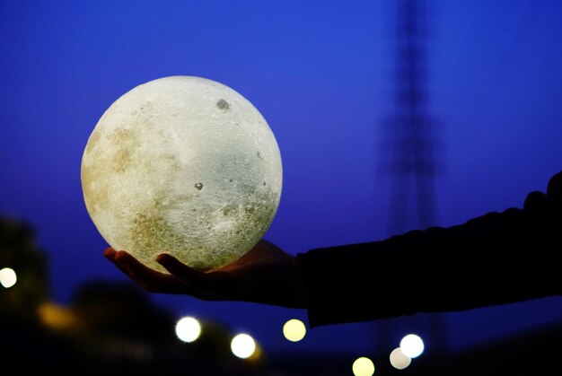 Close-up of hand holding moon against sky at night