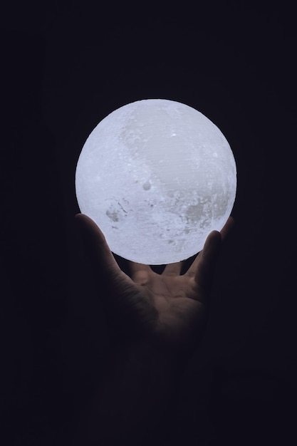 Photo close-up of hand holding moon over black background