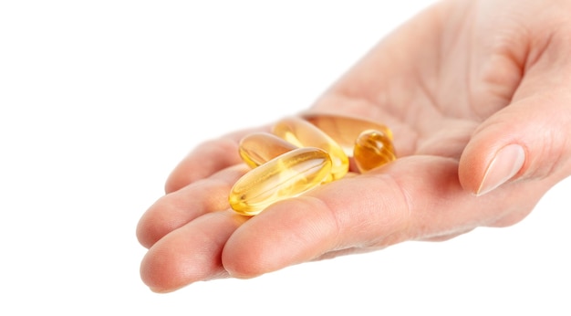 Close up of hand holding Omega 3 soft gel capsules on white background. Copy space. High quality photo
