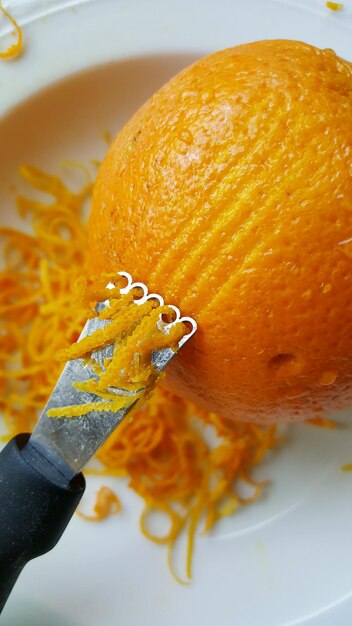 Close-up of hand holding orange slice in plate