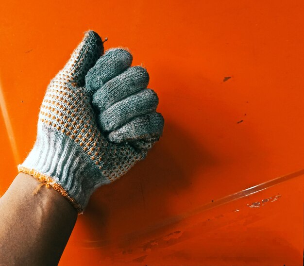 Close-up of hand holding orange wall