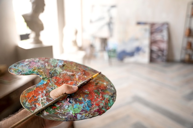 close up hand holding painting palette