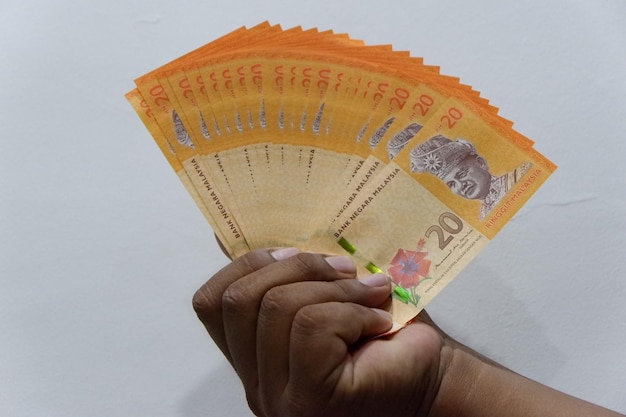 Close-up of hand holding paper against white background