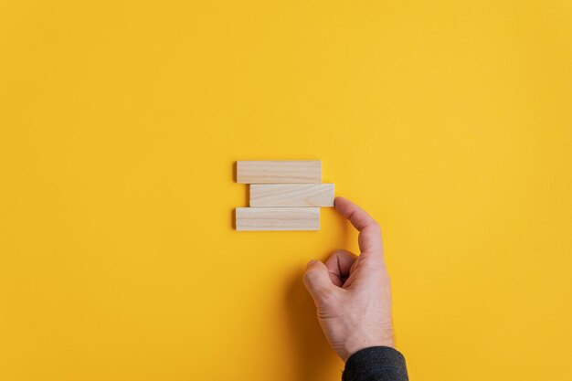 close-up of hand holding paper against yellow background