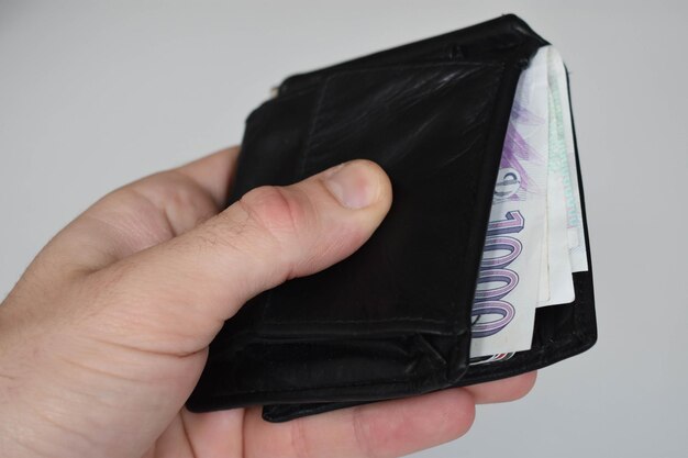 Photo close-up of hand holding paper currency in wallet against white background