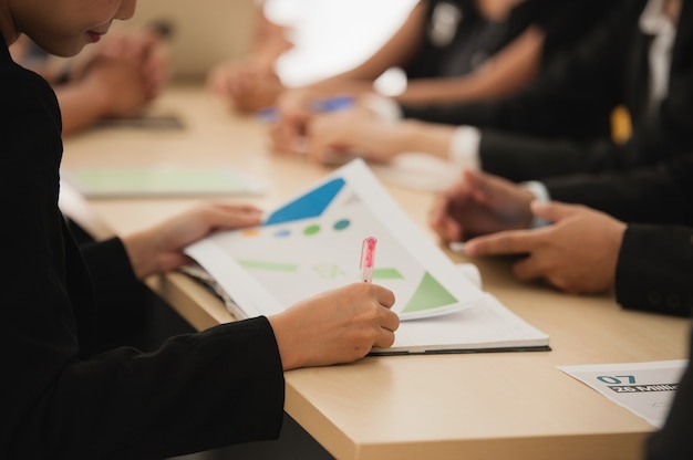 Close up hand holding paper report in group businesspeople meeting