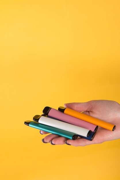 Close-up of hand holding pencils against yellow background
