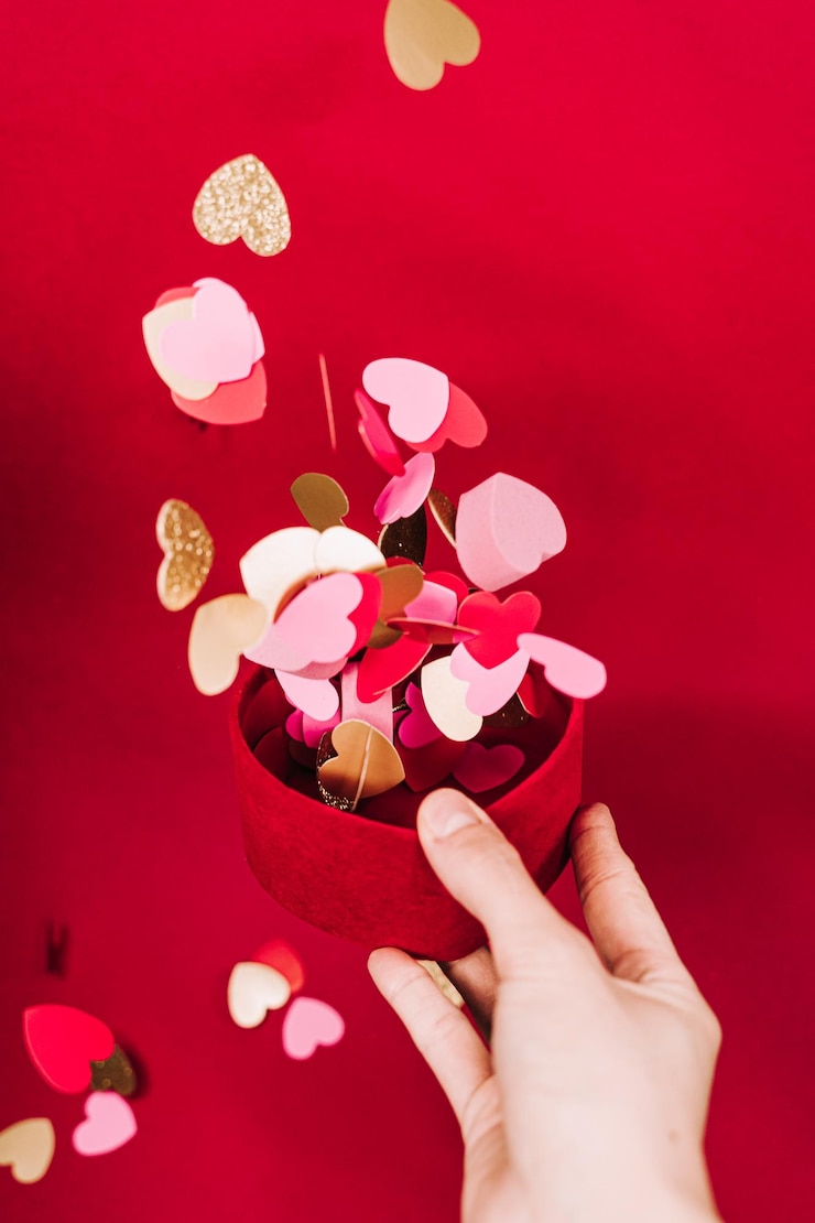 Photo 赤い背景にピンクの花を握っている手のクローズアップ