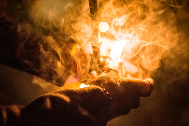 Photo close-up of hand holding pipe amidst smoke