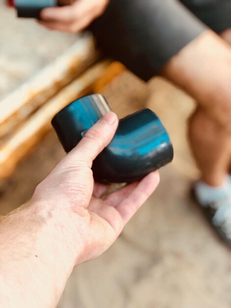 Photo close-up of hand holding pipe by person sitting