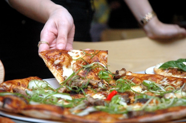 Close-up of hand holding pizza on table