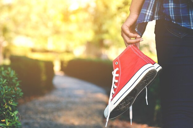 Photo close-up of hand holding red canvas shoes