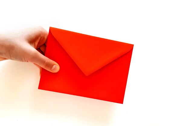 Close-up of hand holding red envelope over white background