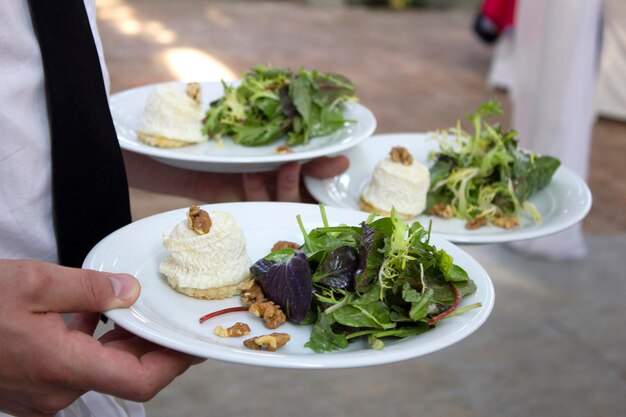 Foto close-up di una mano che tiene un'insalata in un piatto su un tavolo