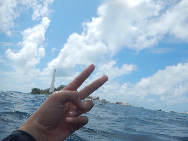 Close-up of hand holding sea against sky