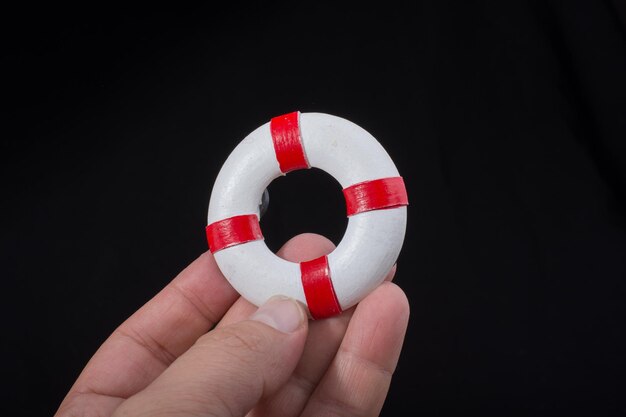 Photo close-up of hand holding small life belt against black background