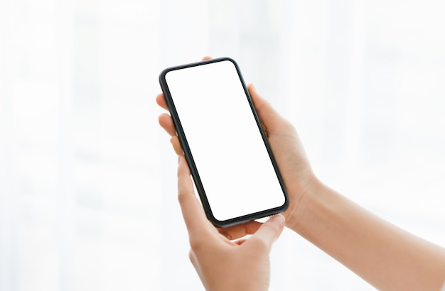 Close up of hand holding smartphone with white mock-up screen.