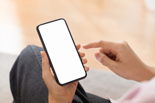 Close up of hand holding smartphone with white mock-up screen.