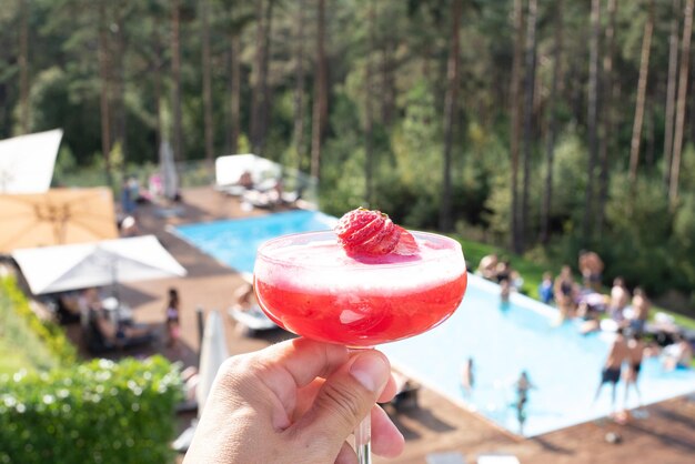 Close-up of hand holding strawberry against trees