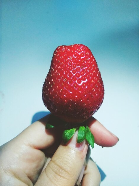 Photo close-up of hand holding strawberry