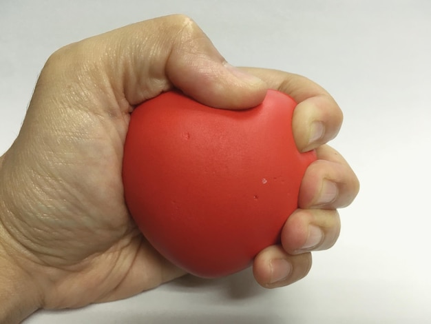 Foto close-up della mano che tiene la palla di stress su uno sfondo bianco