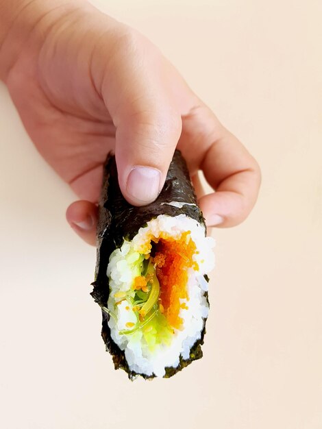 Photo close-up of hand holding sushi against white background