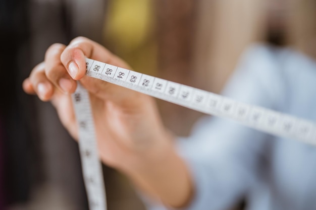 close up of hand holding tape measure for making a dress