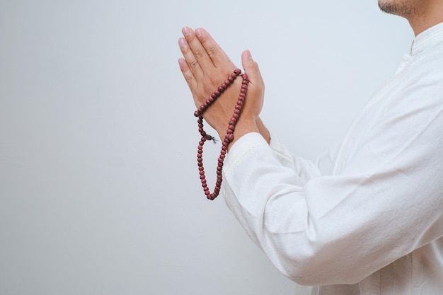 Close up Hand holding a tasbih or prayer beads on white background