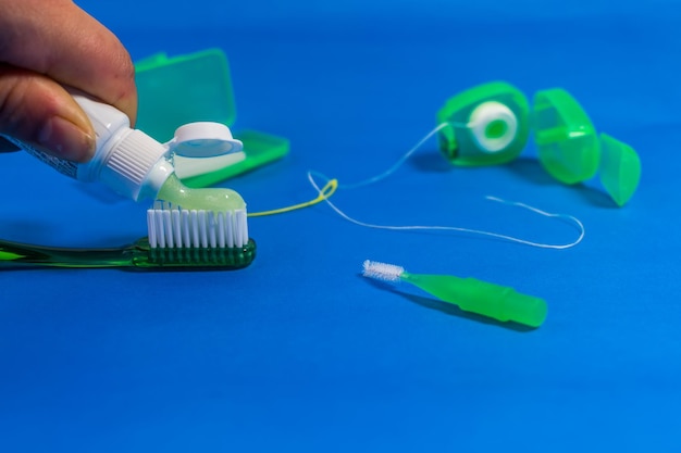 Photo close-up of hand holding toothpaste over brush by equipment against blue background