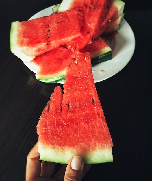 Close-up of hand holding watermelon slice