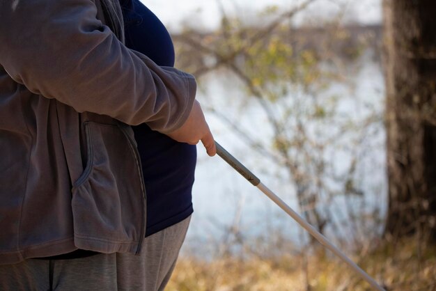 Close up of a hand holding a white cane with a waterway in the background person