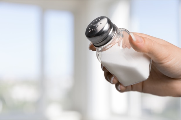 Close up of hand holding white salt cellar