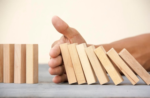 Foto close-up di una mano che tiene dei blocchi di legno su un tavolo