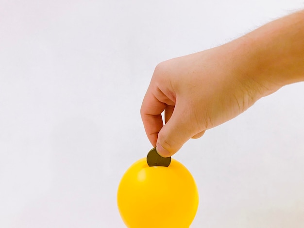 Photo close-up of hand holding yellow flower against white background