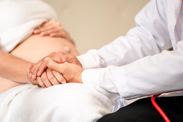 Close up of Hand holdinghands patient have consultation with pregnant woman in hospitalFemale gynecologist talk consult female check pregnancy before giving birthMaternity concept