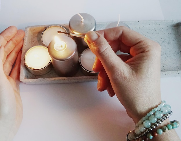 Close-up of hand igniting candles on table