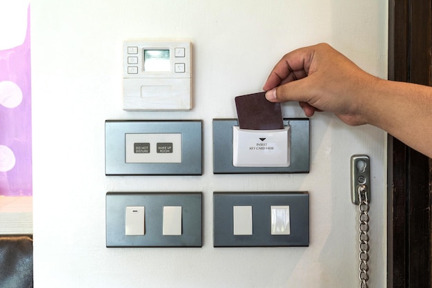 Close up hand insert secue card to the into the resort hotel bedroom electric control platform