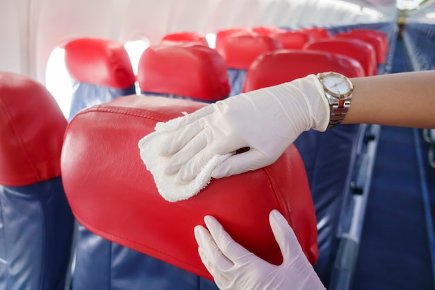 Close up hand is wearing gloves cleaning aircraft seat for covid-19 prevention pandemic