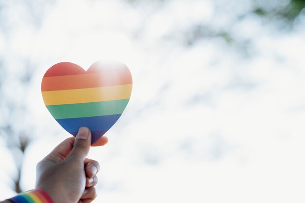 Close up hand of LGBTQ couple holding rainbow heart.