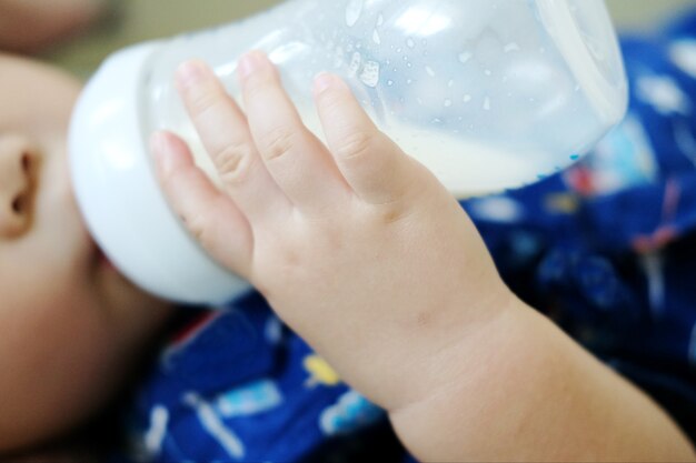 Close-up hand of little baby holding bottle of milk for drinking milk.Feeding baby