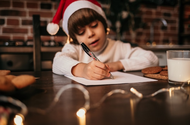 キッチンに座って新年のメッセージを書いている小さな男の子の手のクローズアップ