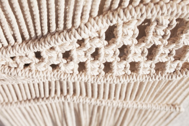 Primo piano del reticolo di struttura del macramè fatto a mano. concetto di decorazione naturale fai-da-te fai-da-te moderno ecologico all'interno. macrame fatto a mano 100% cotone. passatempo femminile.