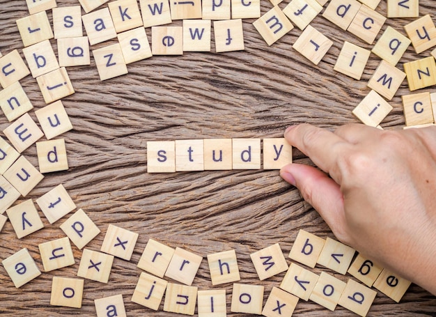 Photo close-up of hand making word with toy blocks