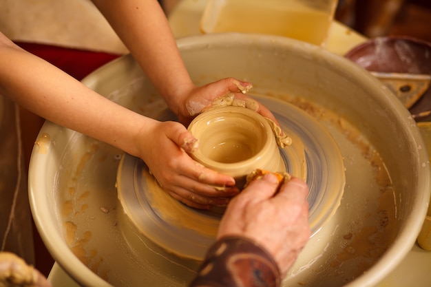 A close-up of the hand of a male potter who teaches his pupil